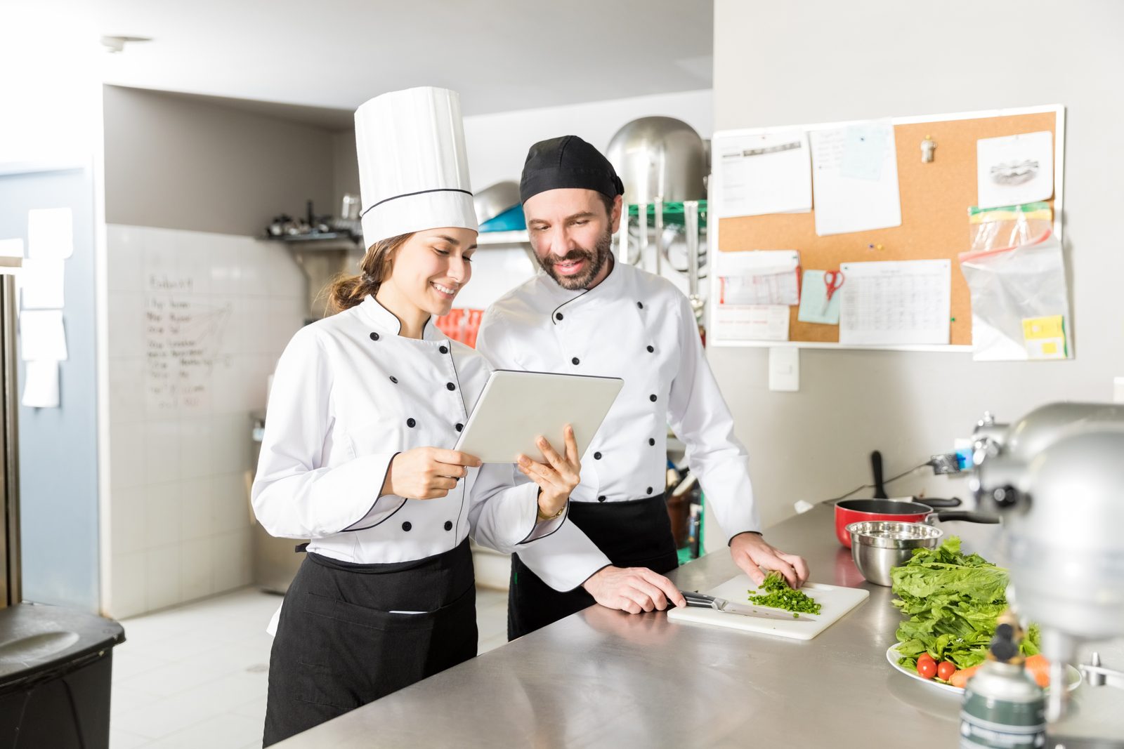 Deux cuisiniers consultant les commandes sur une tablette en cuisine